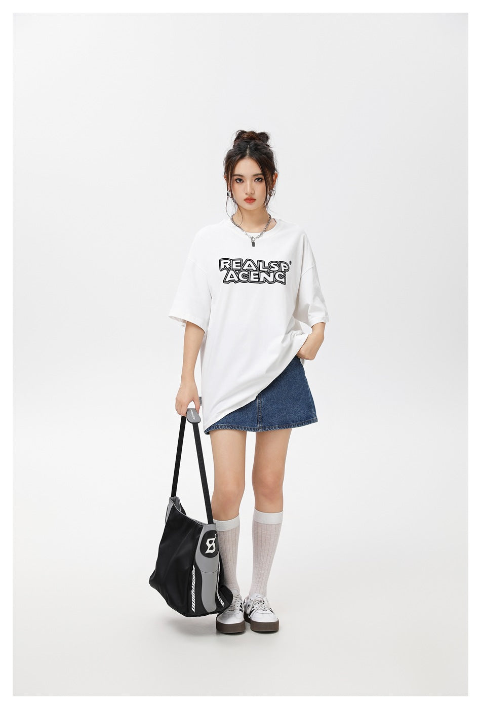 Model wearing a white graphic T-shirt with a blue denim mini skirt, knee socks and sneakers.