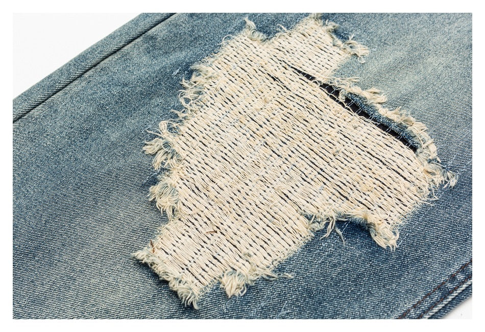 Close-up of a frayed cream woven patch on faded blue denim.