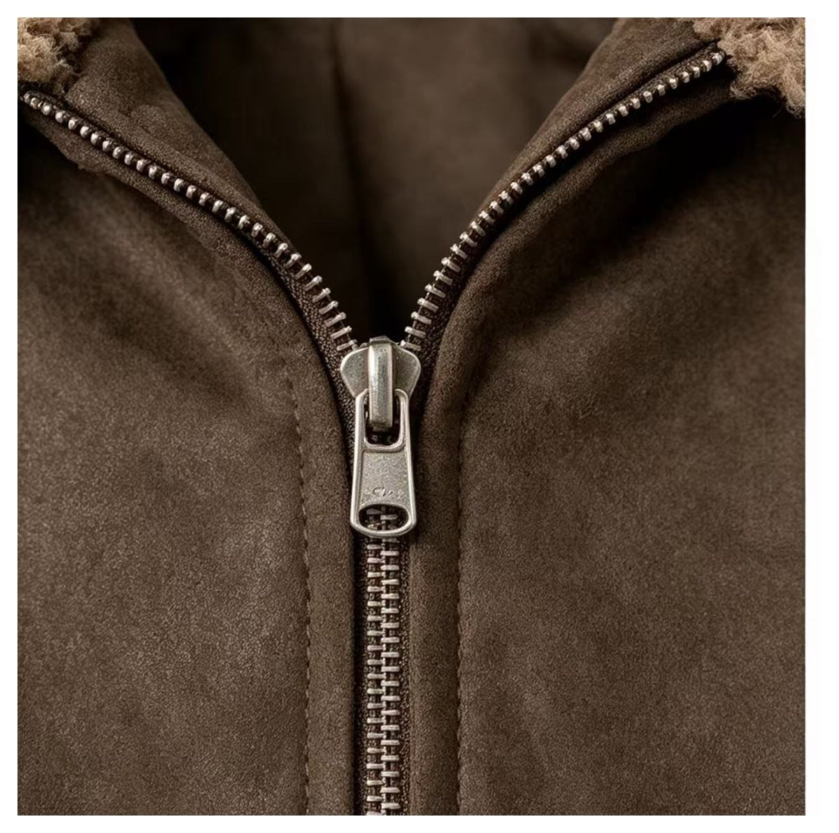 Close-up of a brown jacket’s partially open front zipper with silver teeth and pull.