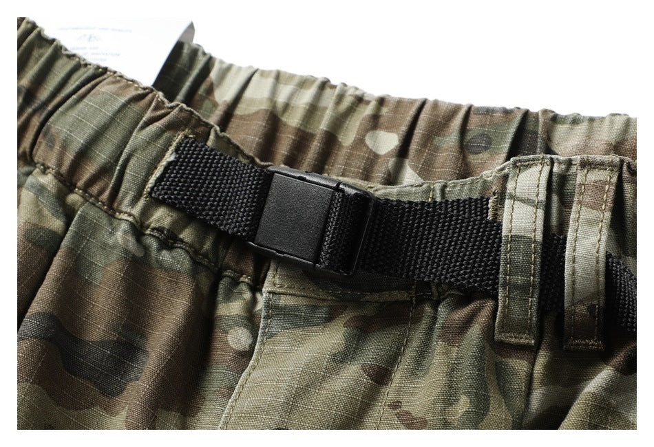 Close-up of the camouflage pants' elastic waistband, black adjustable belt buckle, and belt loops.