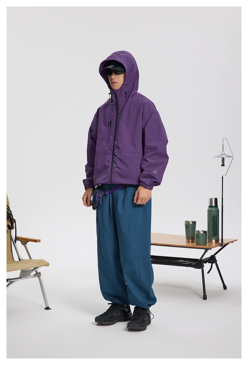 Model wearing a purple hooded jacket with blue trousers, shown from the front.