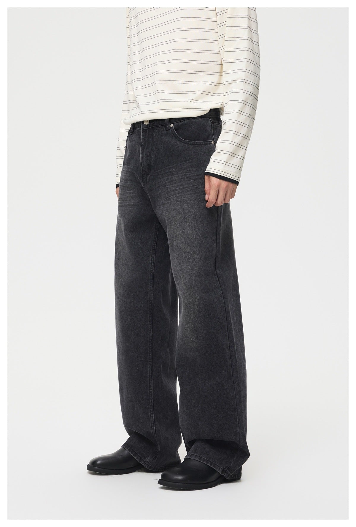 Model wearing dark charcoal wide-leg jeans, shown from the front with a striped shirt and black shoes.