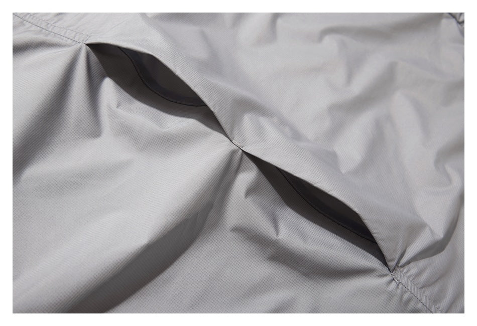Close-up of light gray grid-textured garment fabric showing two dark openings along a stitched seam.