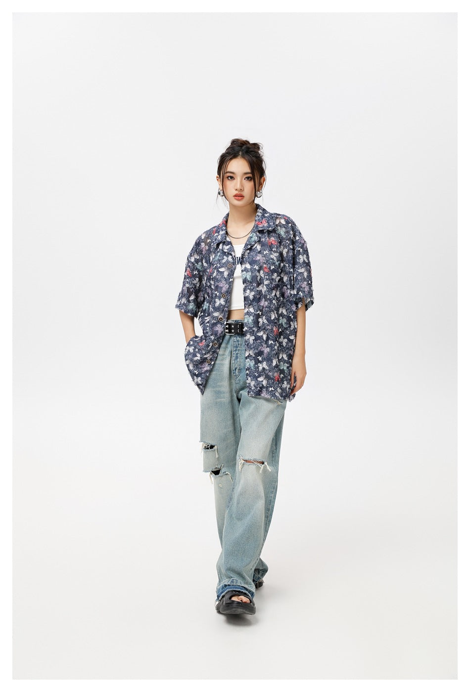 Model wearing an oversized navy butterfly-print button-up shirt with ripped light-wash jeans.