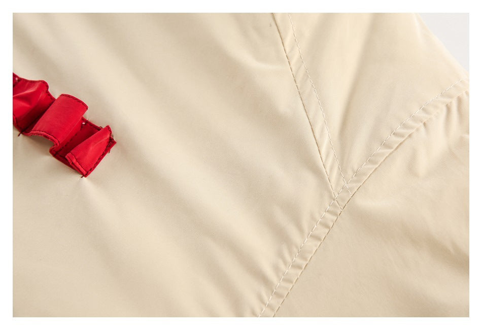Close-up of the cream jacket's stitched panel seams and part of a red fabric detail.