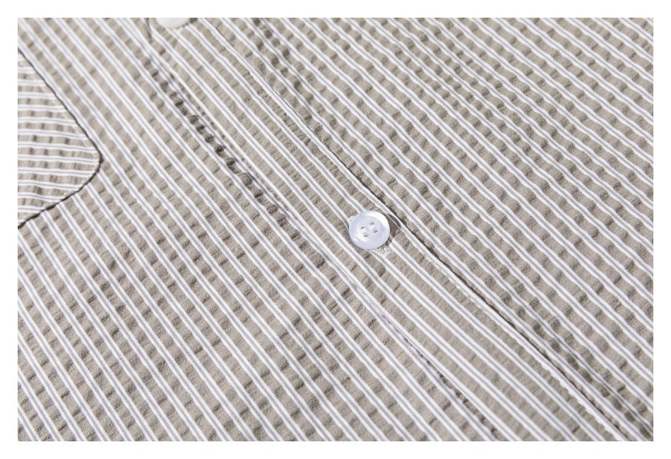 Close-up of a white button on taupe-and-white striped shirt fabric.