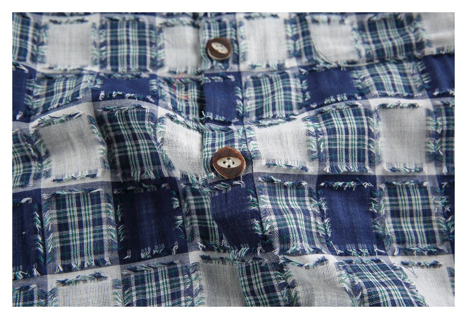 Close-up of the patchwork plaid fabric and a brown button on the garment front.