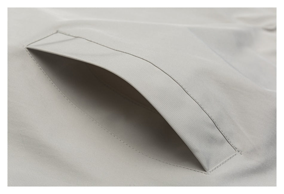 Close-up of a slanted welt pocket on light gray fabric.