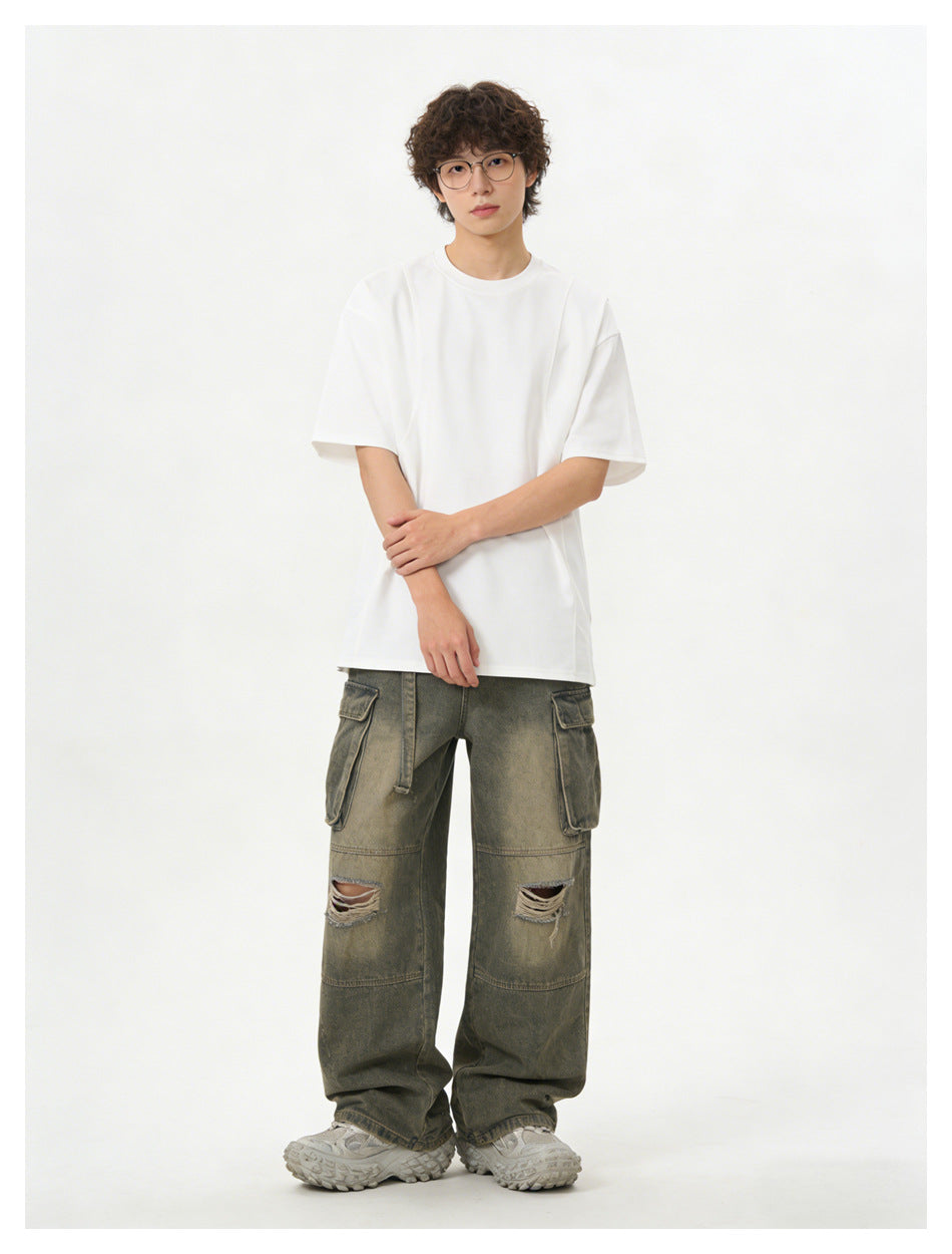 Model wearing an oversized white T-shirt and olive-gray distressed cargo pants, front view.