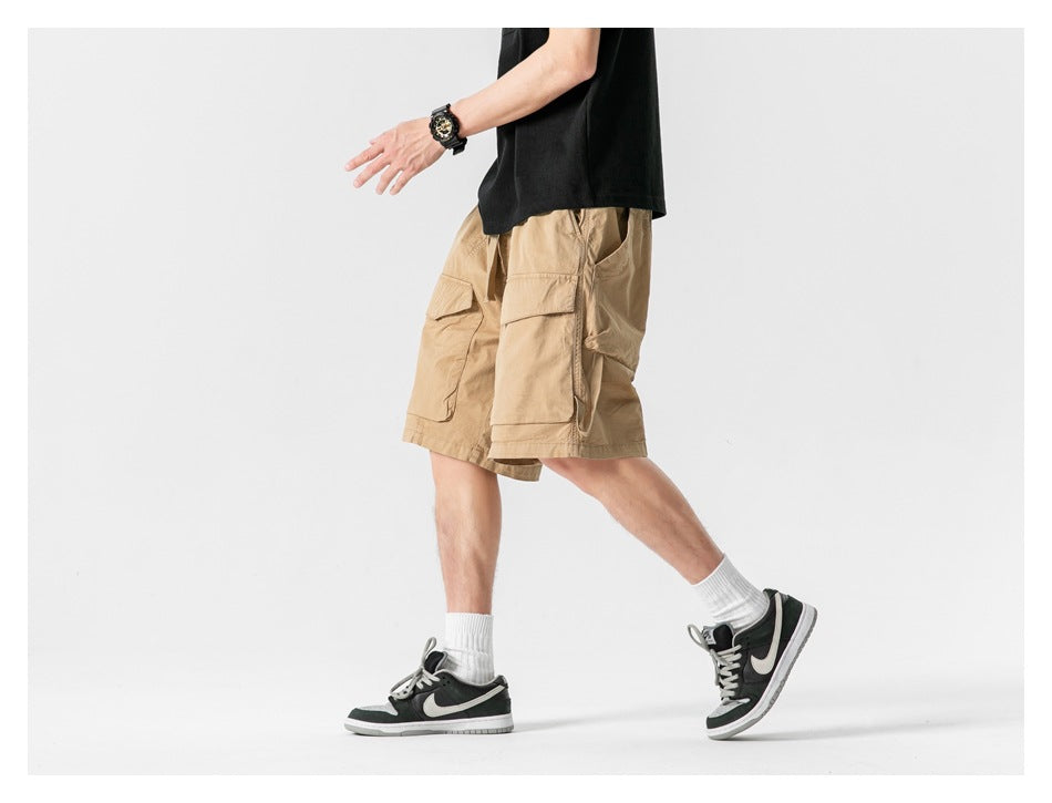 Model in tan cargo shorts, shown walking in a side view against a white studio background.