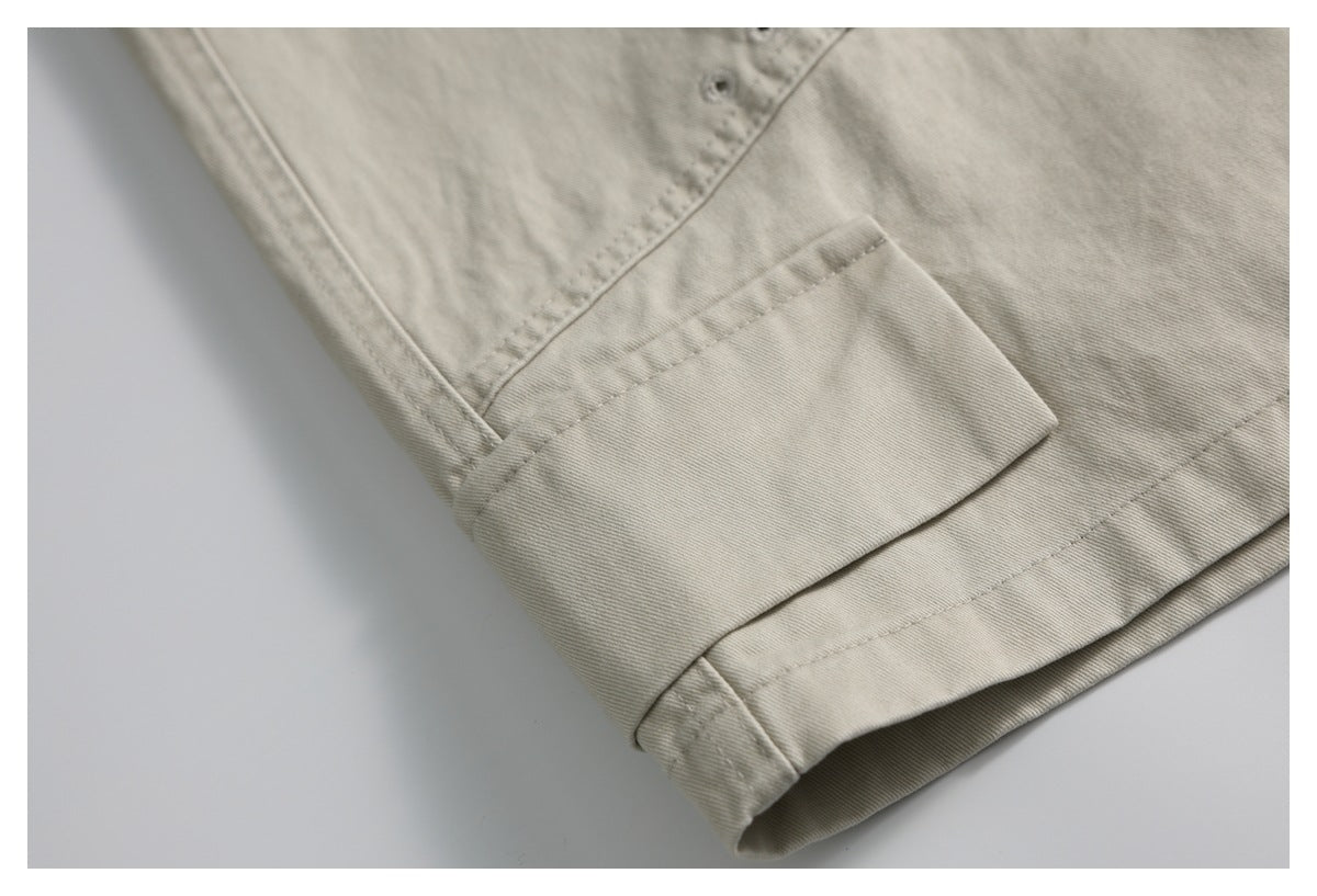 Close-up of a wide cuff on light beige trousers, with nearby stitching and a buttonhole.