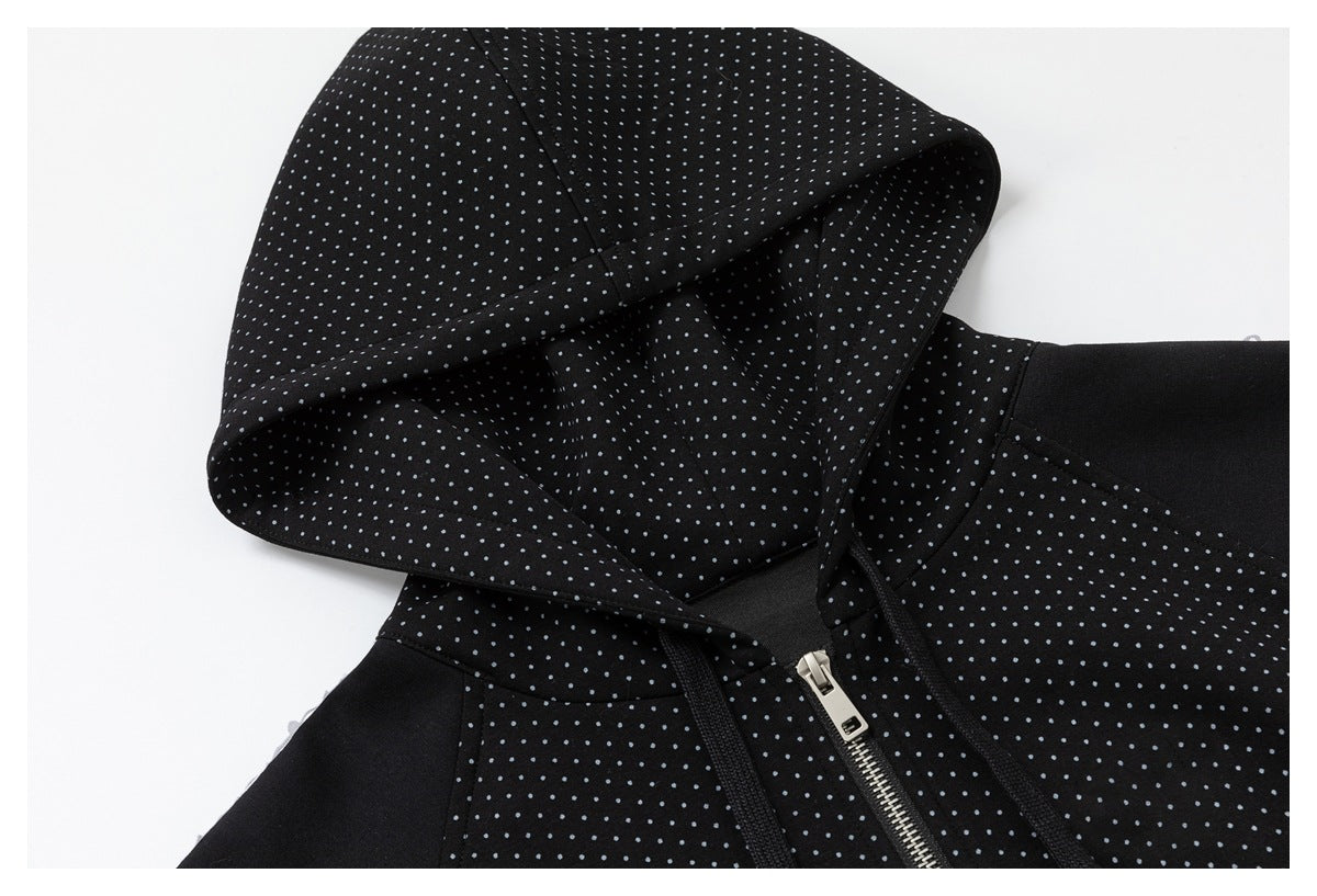 Close-up of the black jacket's dotted hood, drawstrings, shoulder seam, and silver front zipper.
