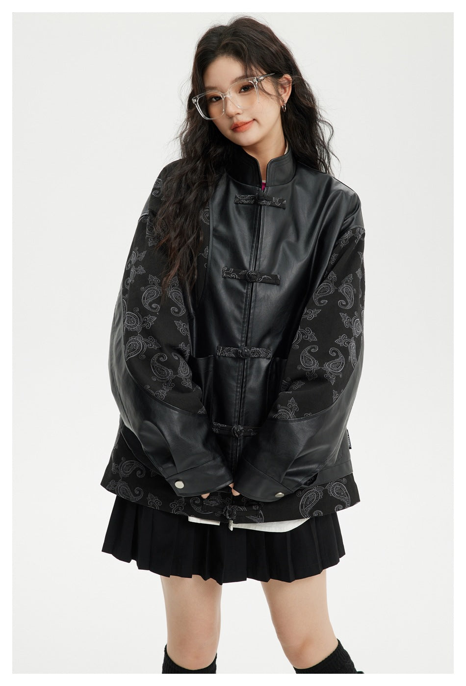 Model wearing a black stand-collar jacket with paisley-patterned sleeves and fabric frog closures.