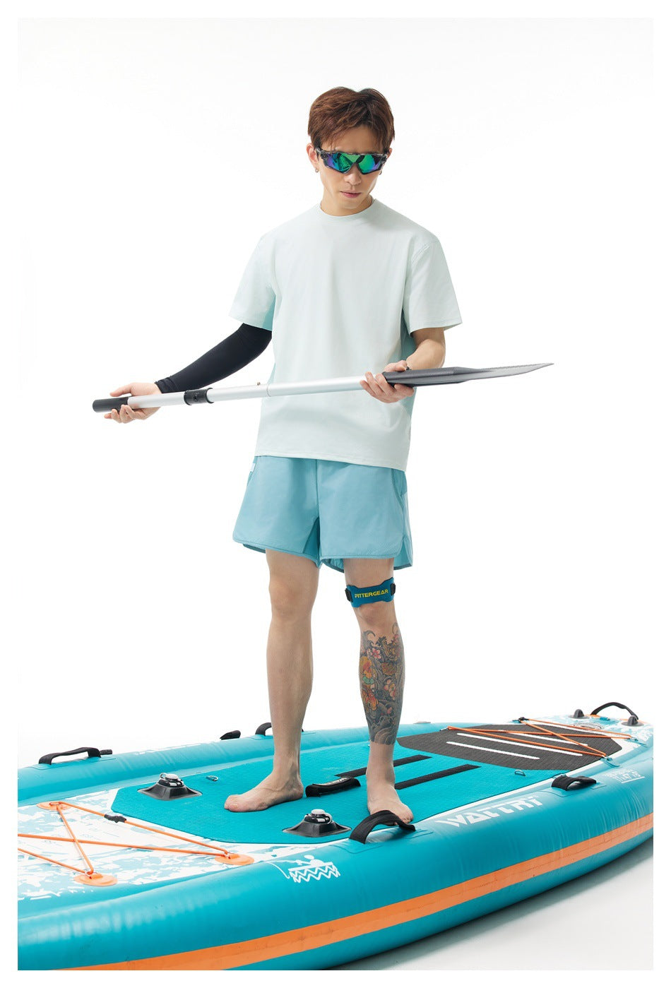 Man in a pale mint short-sleeve T-shirt and light blue shorts holding a paddle on a paddleboard