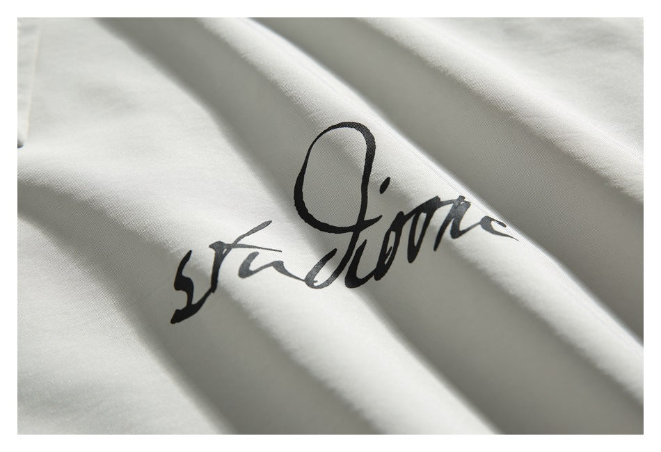 Close-up of a black cursive graphic printed on light ivory shirt fabric.