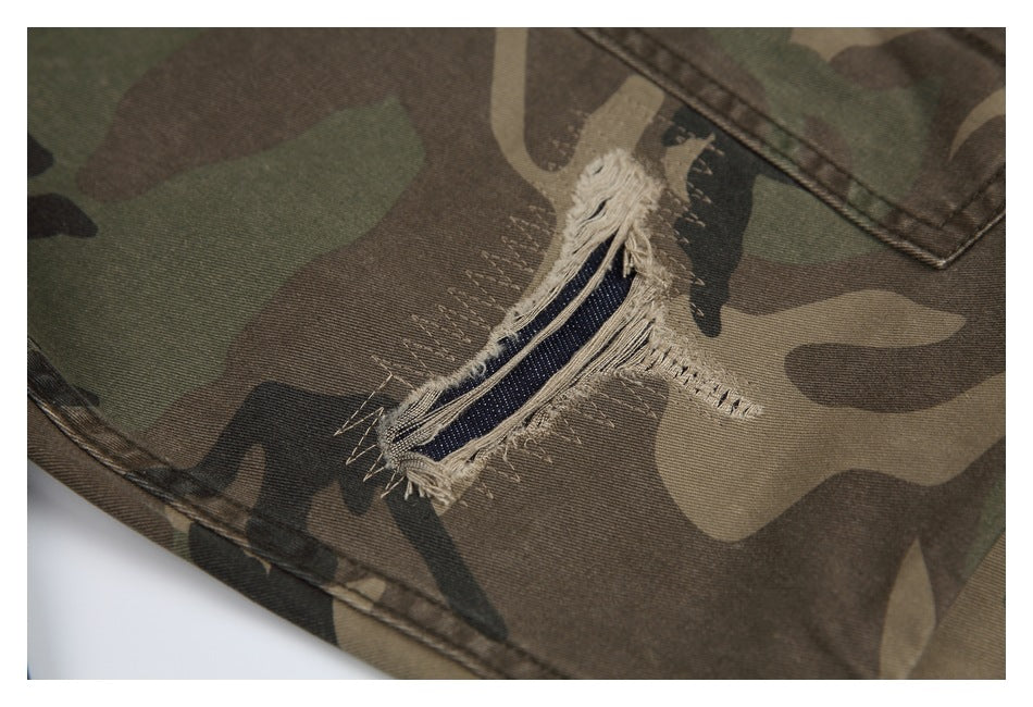 Close-up of a frayed horizontal tear with dark blue threads in camouflage pants.