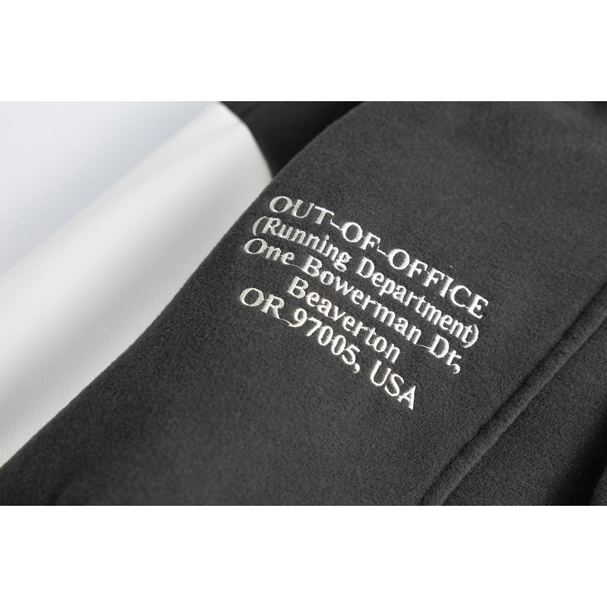 Close-up of white English lettering printed on the charcoal sleeve of a jacket.