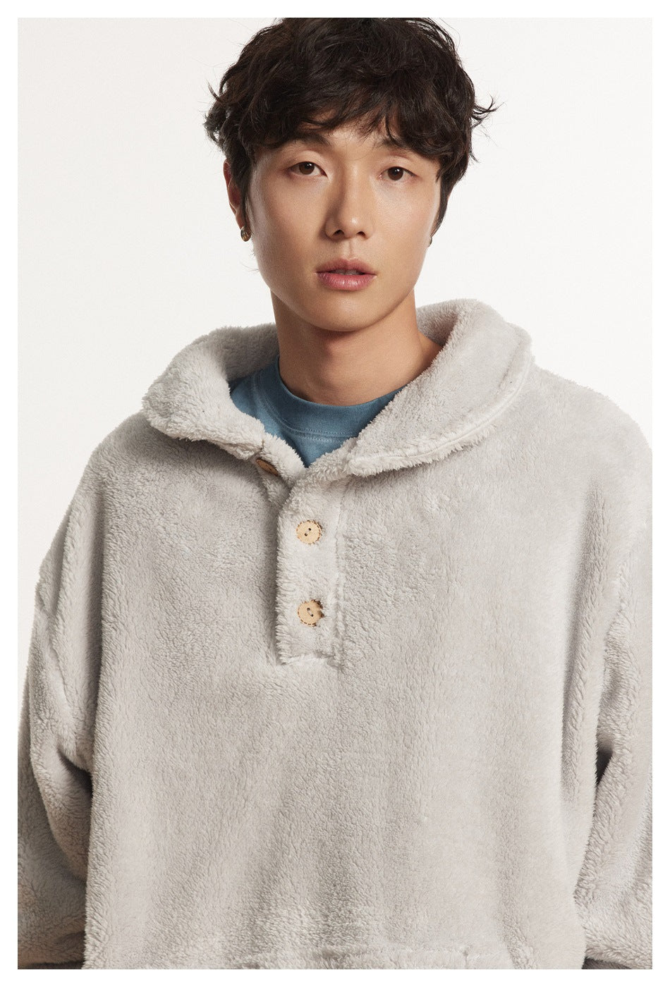 Front close-up of a model wearing a light gray plush pullover with a wide collar and two-button placket.