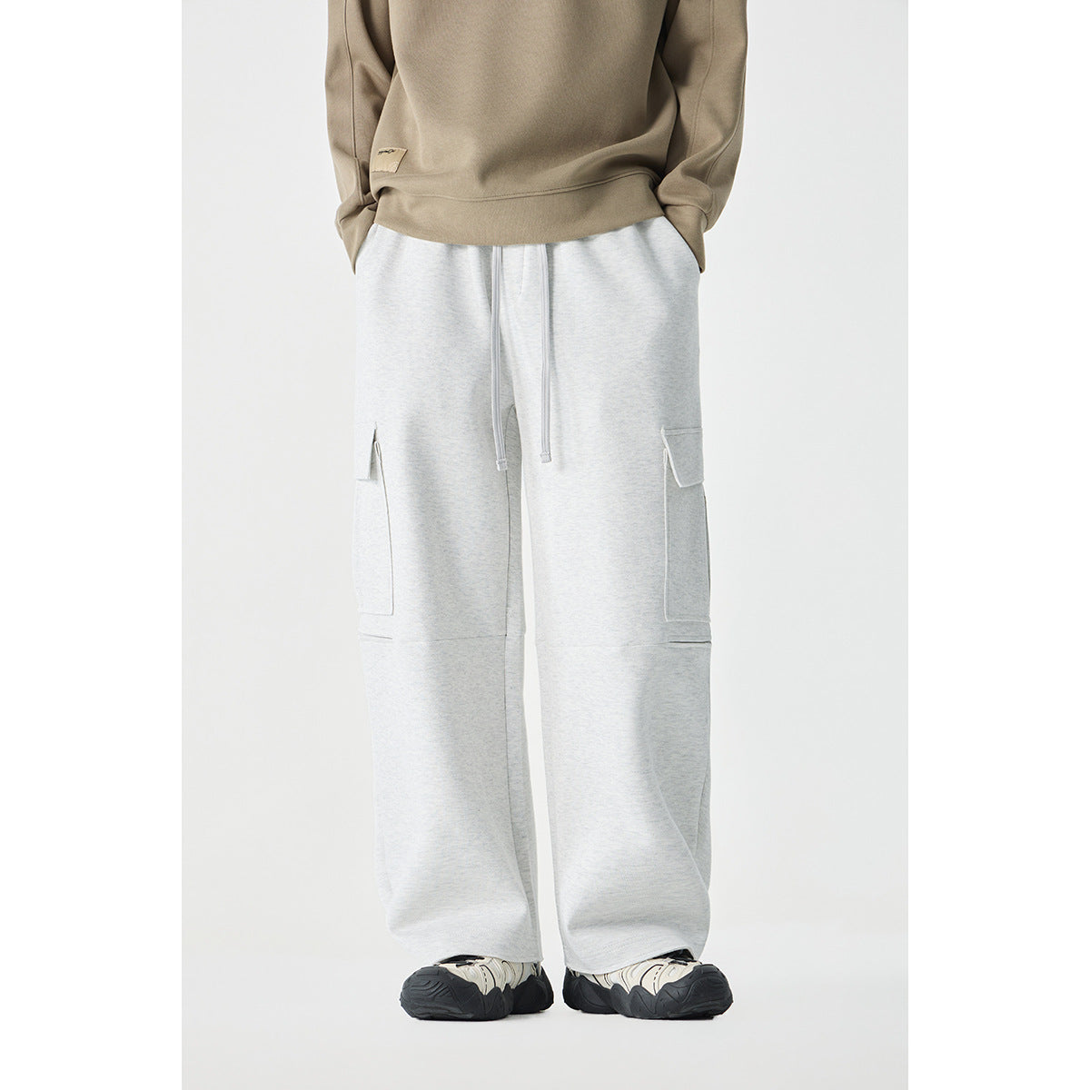 Front view of a model wearing light gray wide-leg cargo pants with drawstrings and flap cargo pockets.