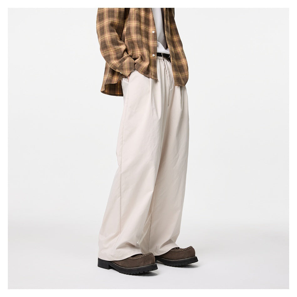Side view of person wearing off-white wide-leg pleated trousers with a plaid shirt and brown chunky shoes