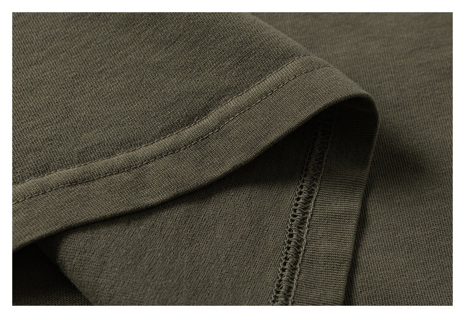 Close-up of olive-gray garment fabric showing a folded edge and overlocked seam.