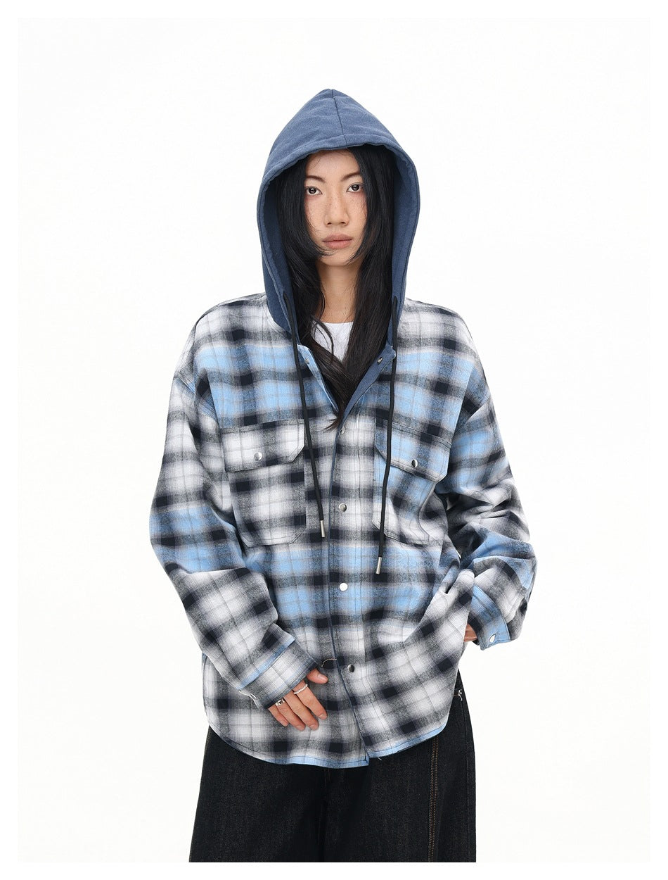 Front view of a model wearing a blue, black, and white plaid shirt with a blue hood, snap buttons, and chest pockets.