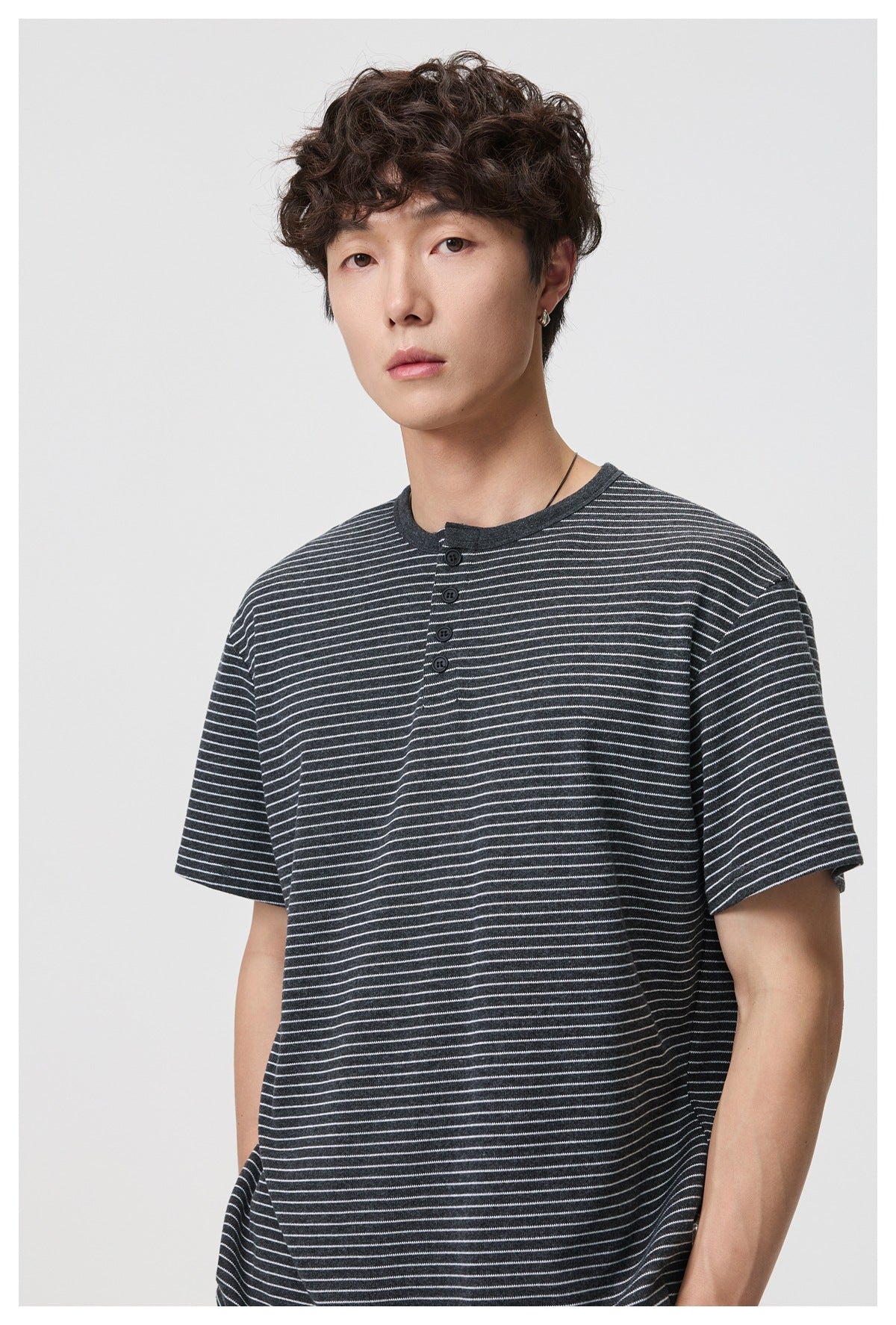 Close-up of a man wearing a dark gray striped short-sleeve Henley T-shirt with black buttons