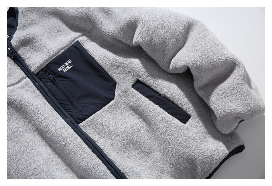 Angled close-up of the gray sherpa jacket front, showing its navy zip chest pocket and slanted hand pocket.