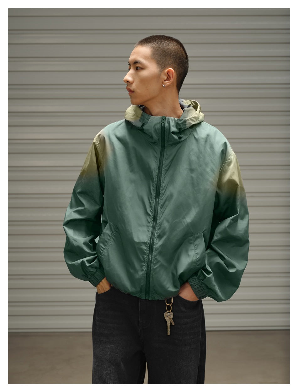 Model wears a sage green hooded zip jacket with olive shoulder accents, shown from the front with his head turned sideways.