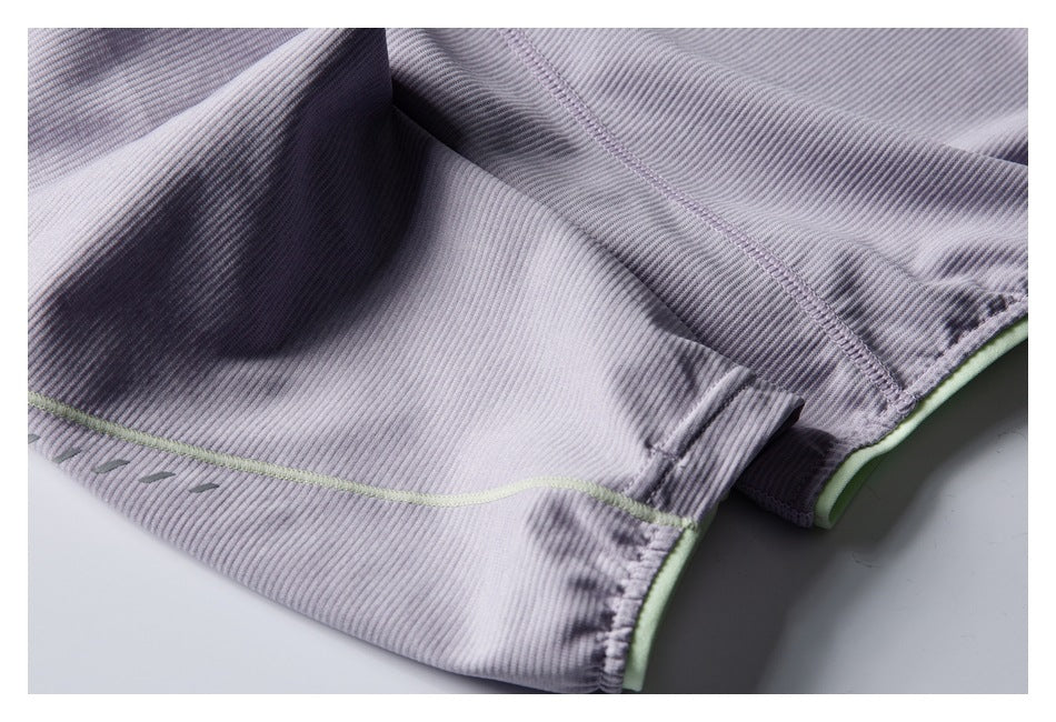 Close-up of the jacket’s lavender fabric, curved seam, pale green piping, and hem trim.