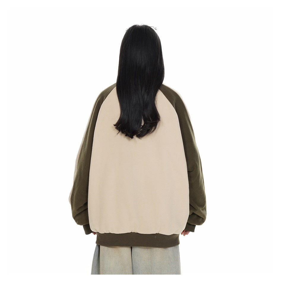 Back view of a model wearing a cream jacket with olive raglan sleeves and a dark olive ribbed hem.