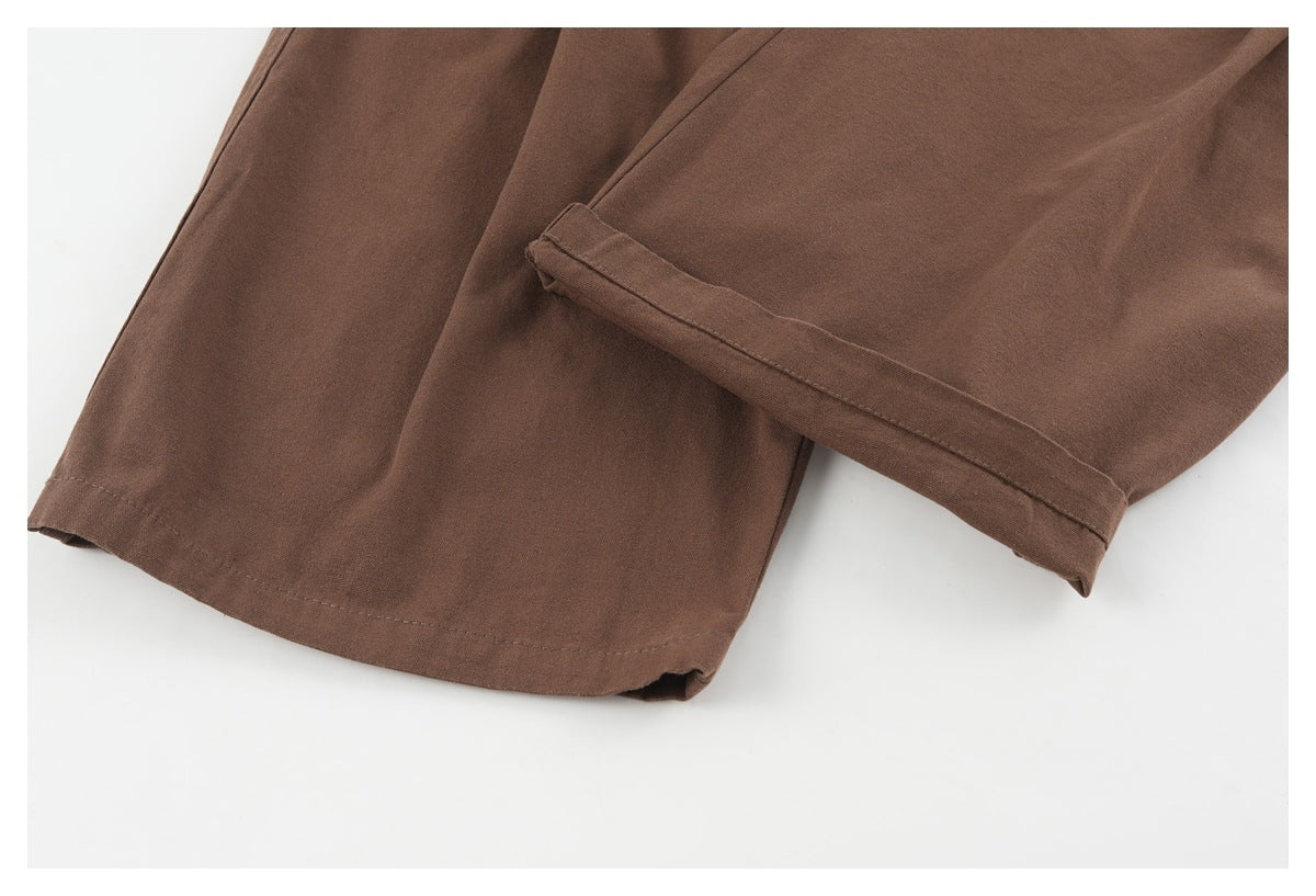 Close-up of the brown trousers' wide leg hems, including one folded cuff.