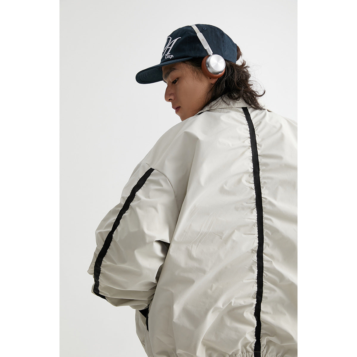 Rear three-quarter view of a model wearing an off-white jacket with black stripes down the back and sleeves.