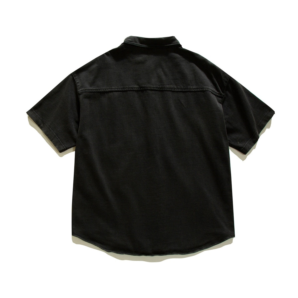 Back view of a black short-sleeve collared shirt laid flat, with a horizontal yoke seam and curved hem.