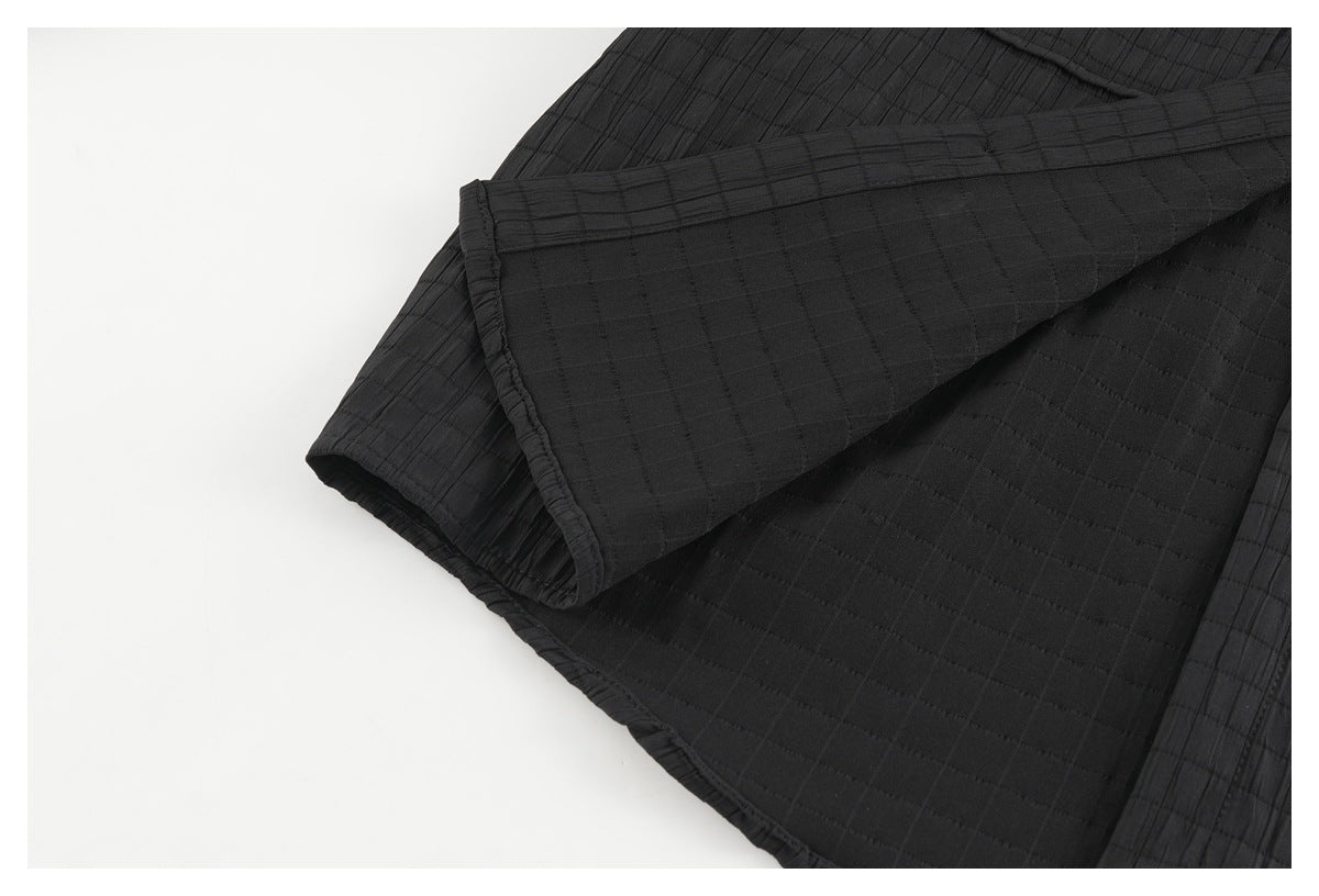 Close-up of the black shirt's folded sleeve and stitched edge, showing its subtle grid texture.