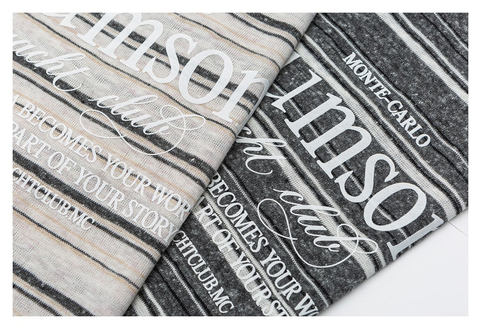 Close-up of cream and charcoal striped shirts with large white English text printed on the fabric.