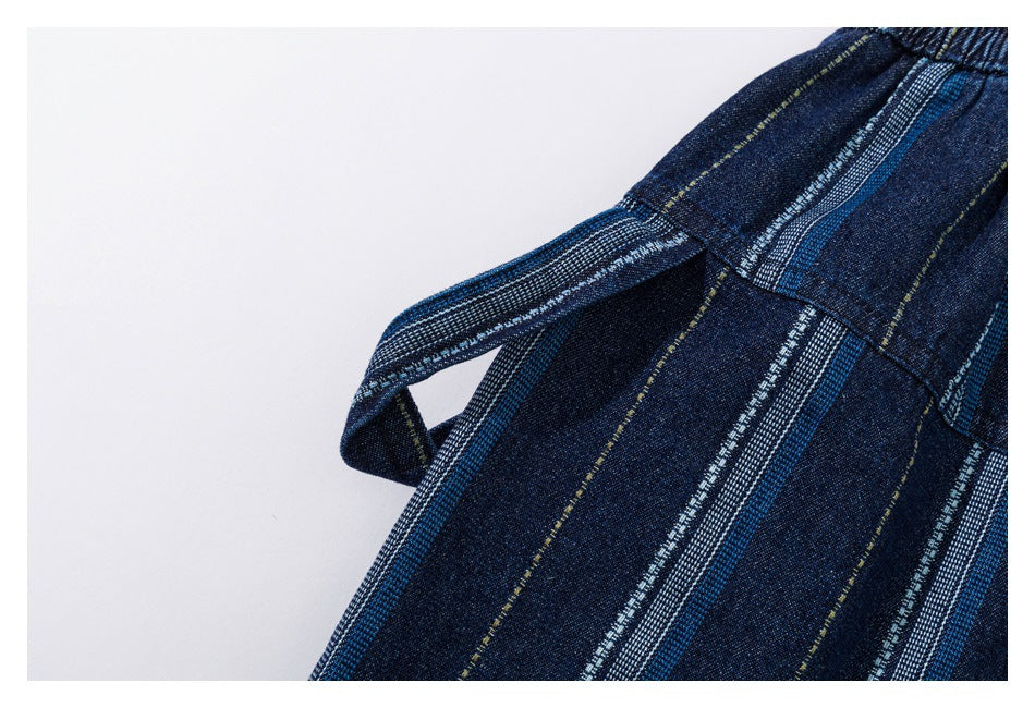 Close-up of a fabric loop and seam on dark blue shorts with blue, white, and fine yellow stripes.