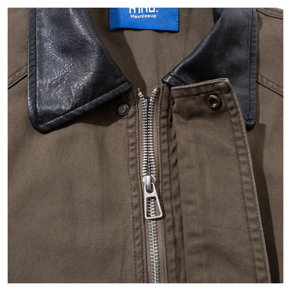 Close-up of a brown jacket with a black collar, silver zipper, snap fastener, and blue neck label.