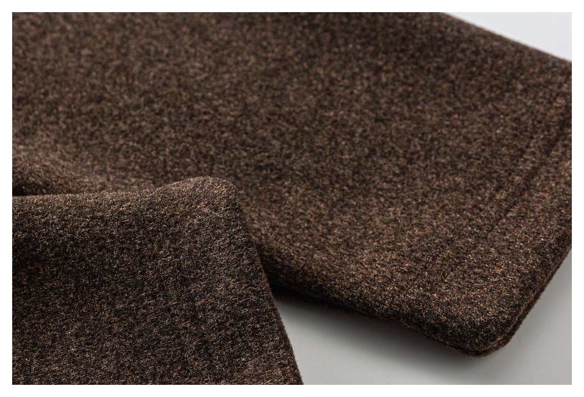 Close-up of brown textured garment fabric with a folded, stitched edge.