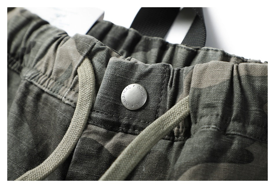 Close-up of the camouflage pants’ elastic waistband, drawcord, and metal button.