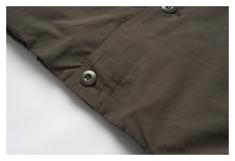 Close-up of two buttons along the stitched front closure of the brown jacket.
