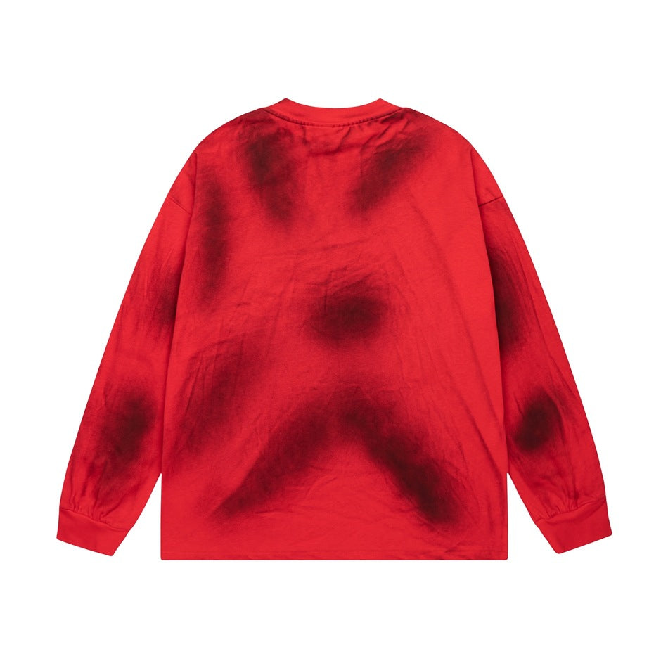 Back view of a red long-sleeve crewneck shirt with irregular dark charcoal tie-dye patches.