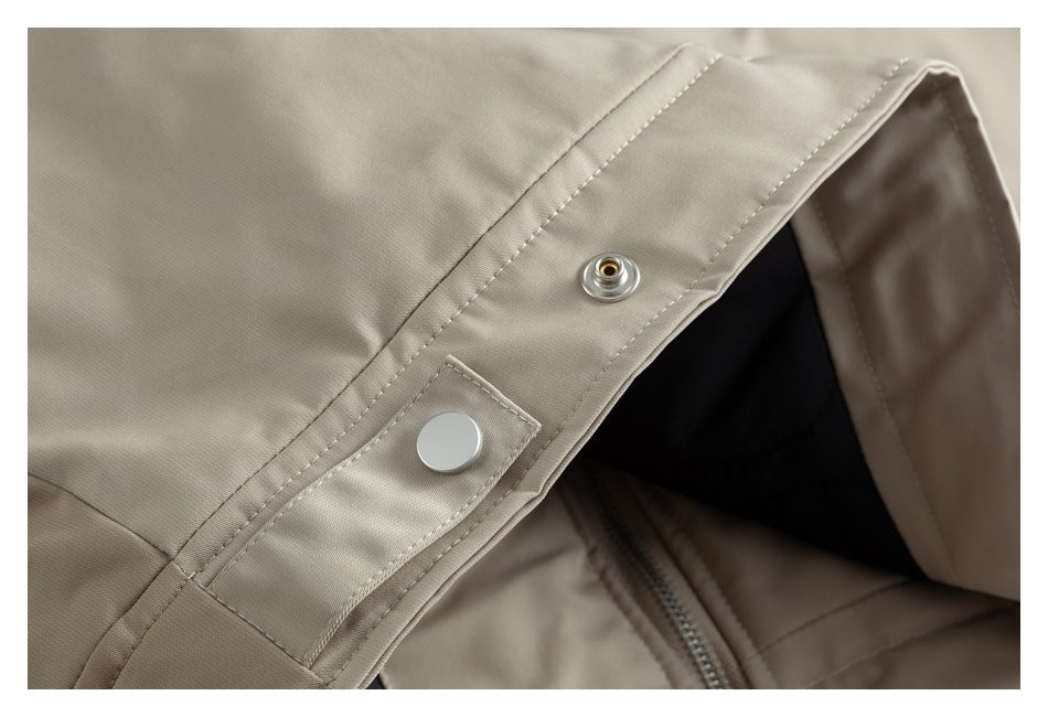 Close-up of beige jacket front with a metal snap closure and zipper beneath.