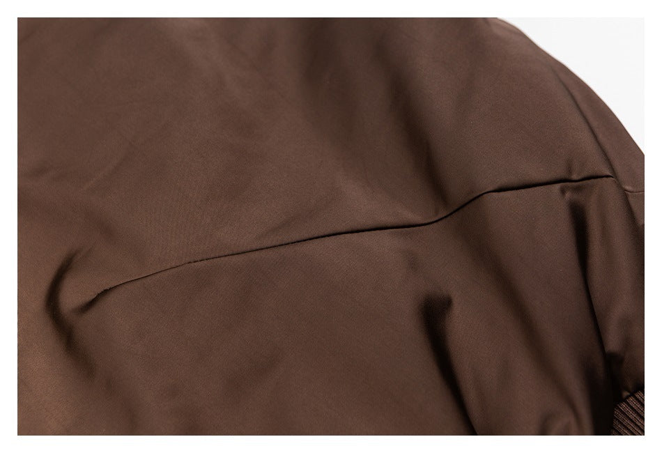 Close-up of a curved seam across the back of a dark brown jacket.