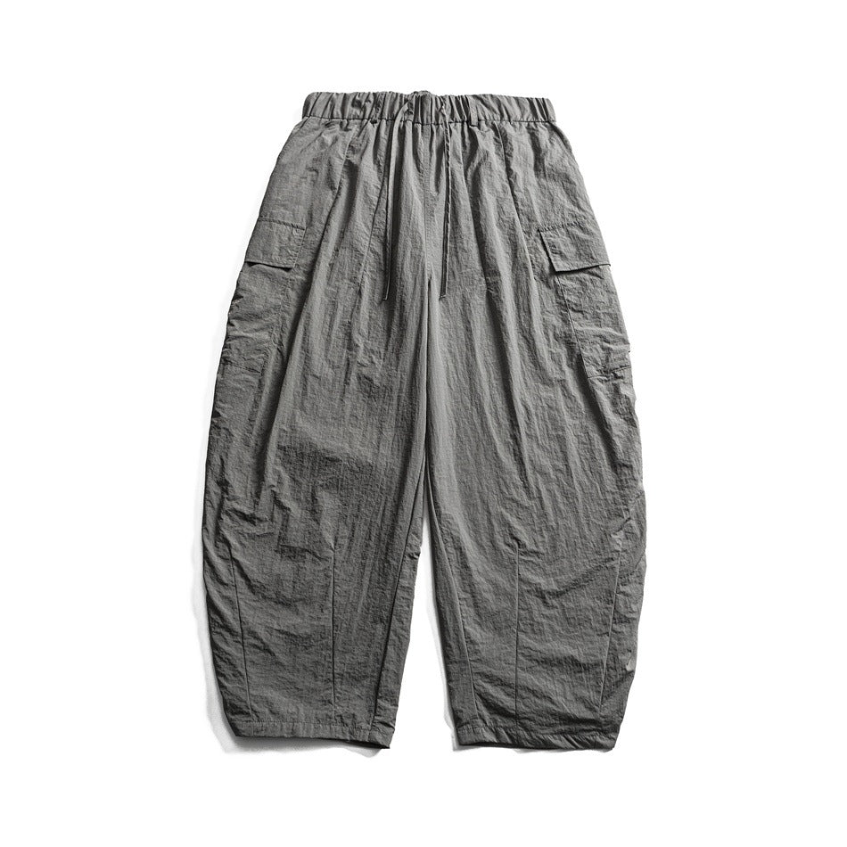 Gray wide-leg cargo pants with elastic drawstring waist and side flap pockets, flat lay on white background