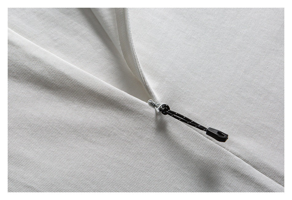 Close-up of a black zipper pull on white fabric.