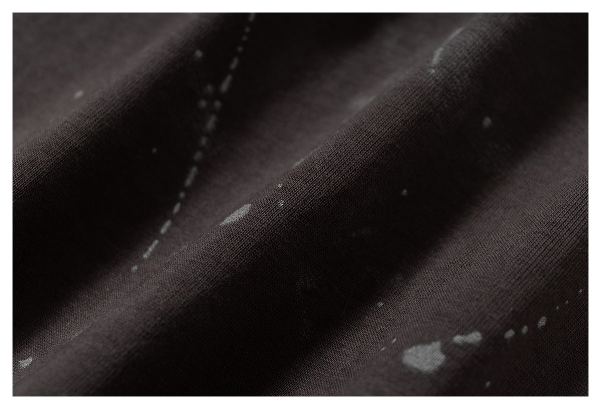 Macro view of dark fabric with a scattered gray splatter pattern.