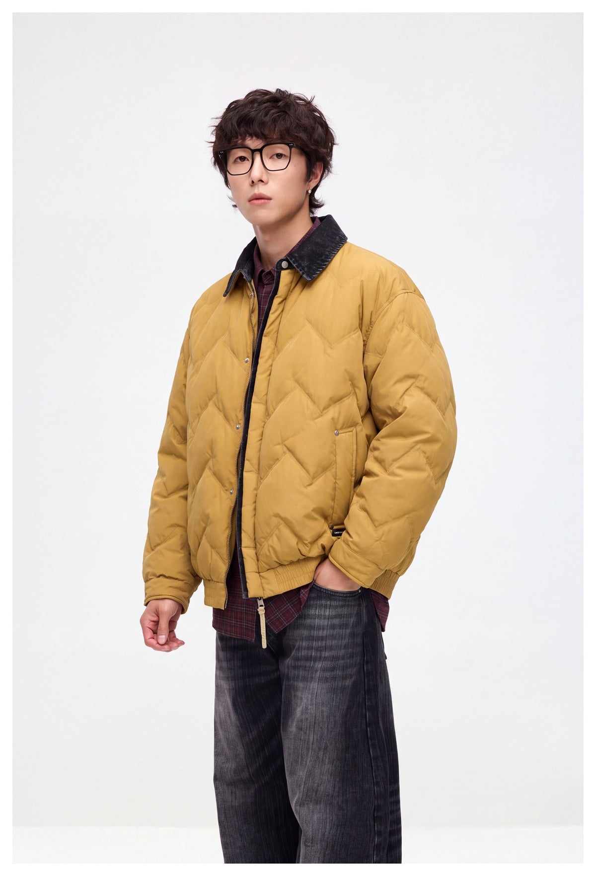 Man in a yellow chevron-quilted jacket with denim-look collar over a plaid shirt, three-quarter view