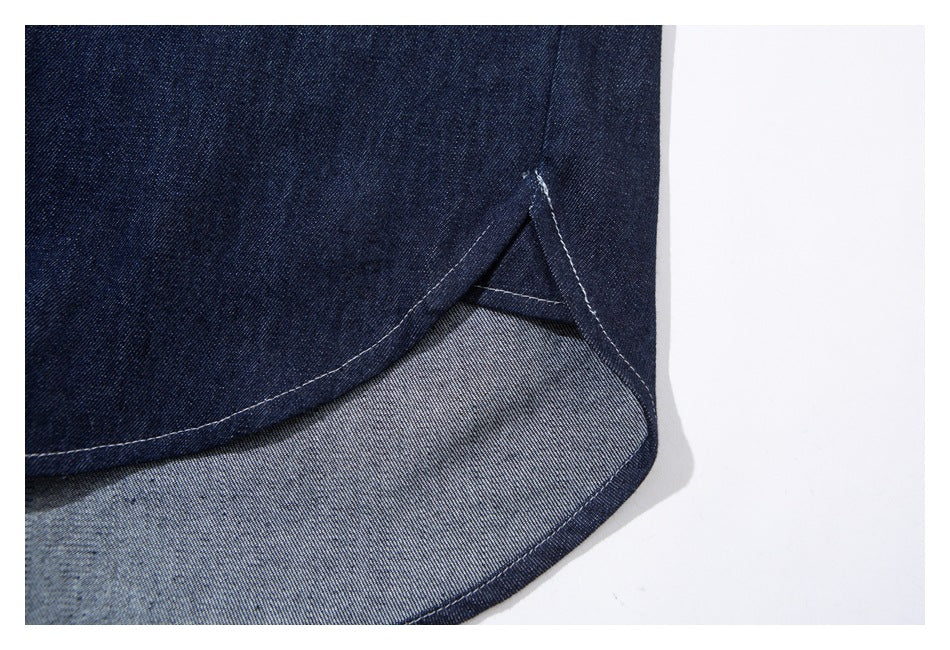 Close-up of a curved dark denim hem with contrast stitching and the lighter reverse side visible.