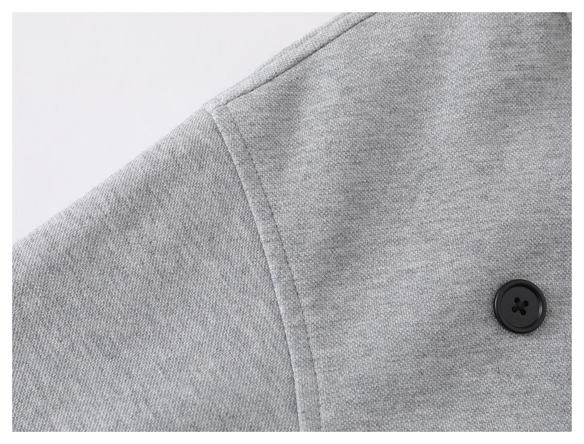 Close-up of a light gray jacket shoulder seam and black button.